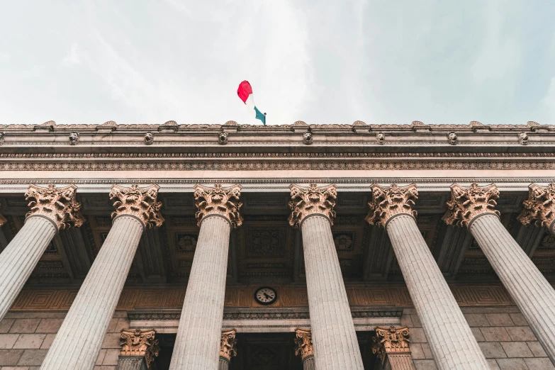 a building with columns and a flag on top of it, pexels contest winner, prefecture streets, view from bottom to top, court session images, facing front