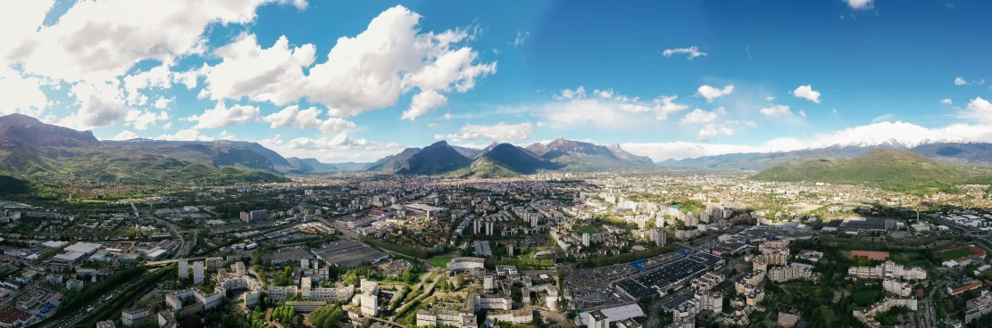 an aerial view of a city with mountains in the background, by Daniël Mijtens, pexels contest winner, ultrawide angle, beautiful day, 4 k cinematic panoramic view, concert