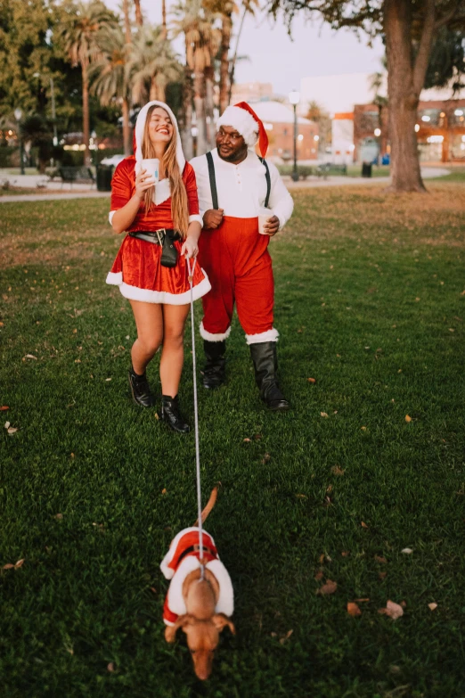 two people dressed as santa claus and a dog, unsplash, happening, walking on grass, thicc, smol, date