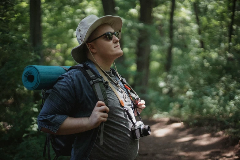 a man with a backpack on a trail in the woods, pexels contest winner, wearing sunglasses and a hat, avatar image, cinematic footage, candid portrait photo