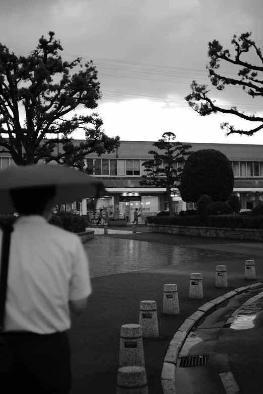 a black and white photo of a person holding an umbrella, a black and white photo, sōsaku hanga, at dusk!, in town, covered!!, summer evening