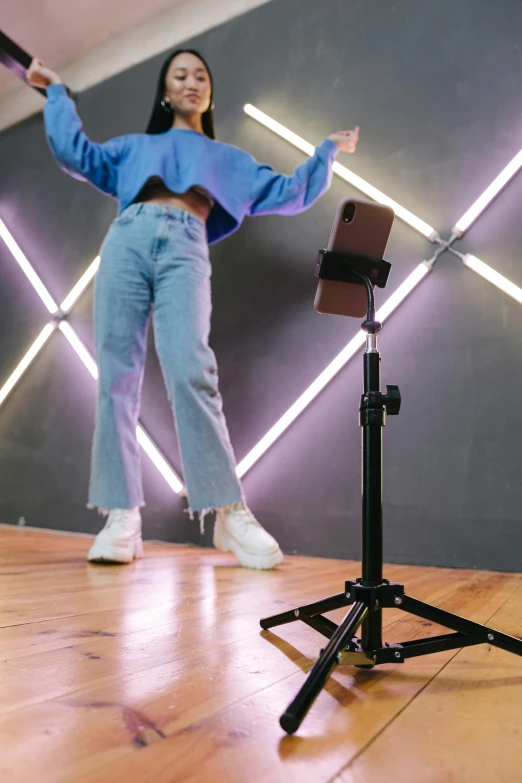 a woman standing on top of a wooden floor, a hologram, trending on pexels, interactive art, studio camera, taking a selfie, battle stand, standing microphones