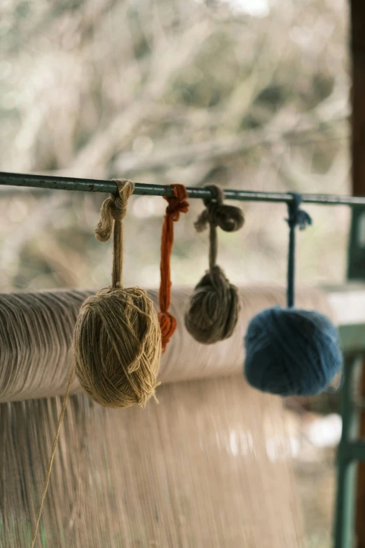 a group of balls of yarn hanging from a rack, unsplash, arts and crafts movement, chile, rural, cinematic still, mill