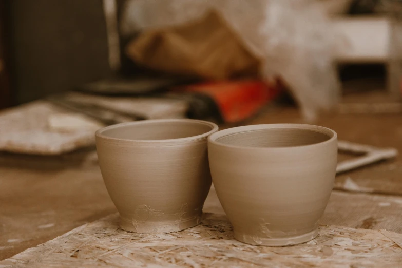 a couple of cups sitting on top of a table, by Fuller Potter, trending on pexels, clay material, unfinished, grey, product introduction photo