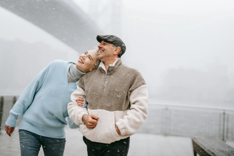 a man and a woman walking in the rain, pexels contest winner, head bent back in laughter, wearing a sweater, bridges, foggy day outside