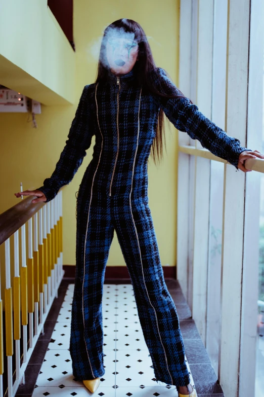 a woman standing on a balcony with a cigarette in her mouth, an album cover, unsplash, hurufiyya, jumpsuits, tartan hoody, standing in a dimly lit room, fullbody view