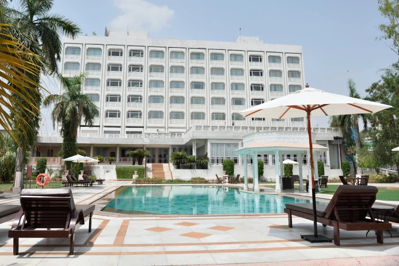 a couple of lawn chairs sitting next to a swimming pool, a portrait, white marble buildings, mogul khan, exterior photo, hotel