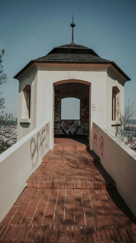 a small white building with graffiti on it, pexels contest winner, stairs and arches, top of the hill, low quality photo, brown