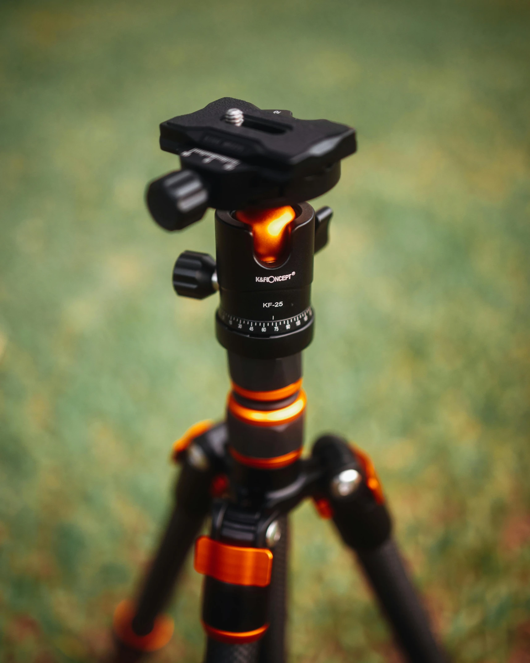 a tripod sitting on top of a green field, pexels contest winner, photorealism, black and orange, high angle close up shot, shot with sony alpha 1 camera, indoor shot