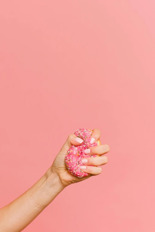 a woman holding a pink donut in her hand, by Julia Pishtar, synthetic bio skin, spiky, shot with sony alpha, nails
