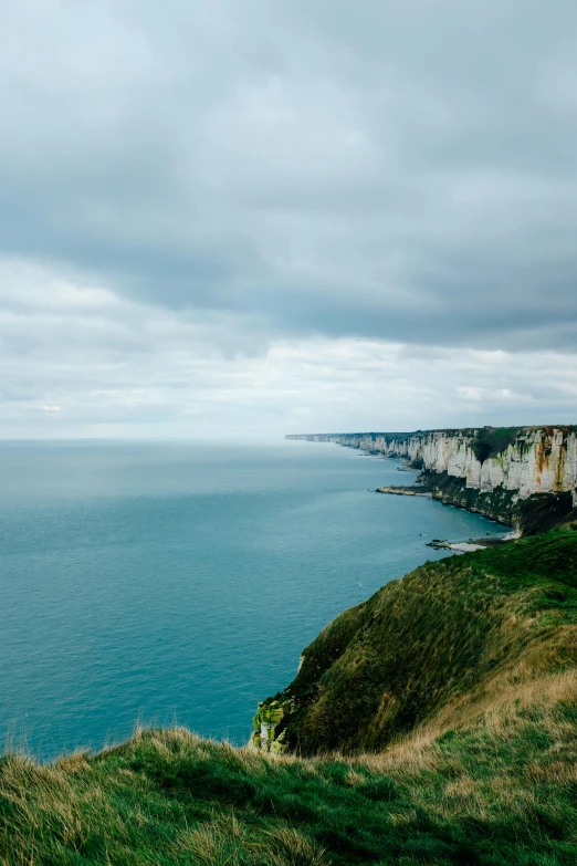 a man standing on top of a cliff next to the ocean, les nabis, normandy, today\'s featured photograph 4k, 4 k -, white stone arches