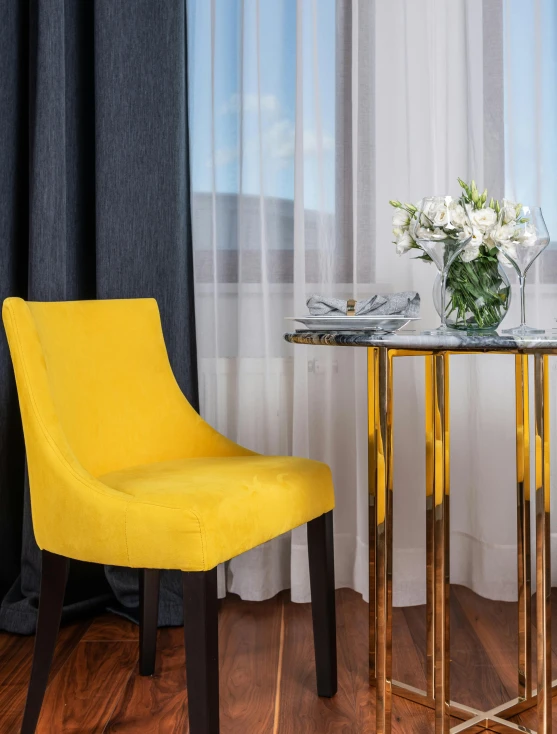 a yellow chair sitting next to a table on top of a hard wood floor, inspired by Constantin Hansen, trending on unsplash, baroque, hotel room, velvet tablecloth, thumbnail, showcase