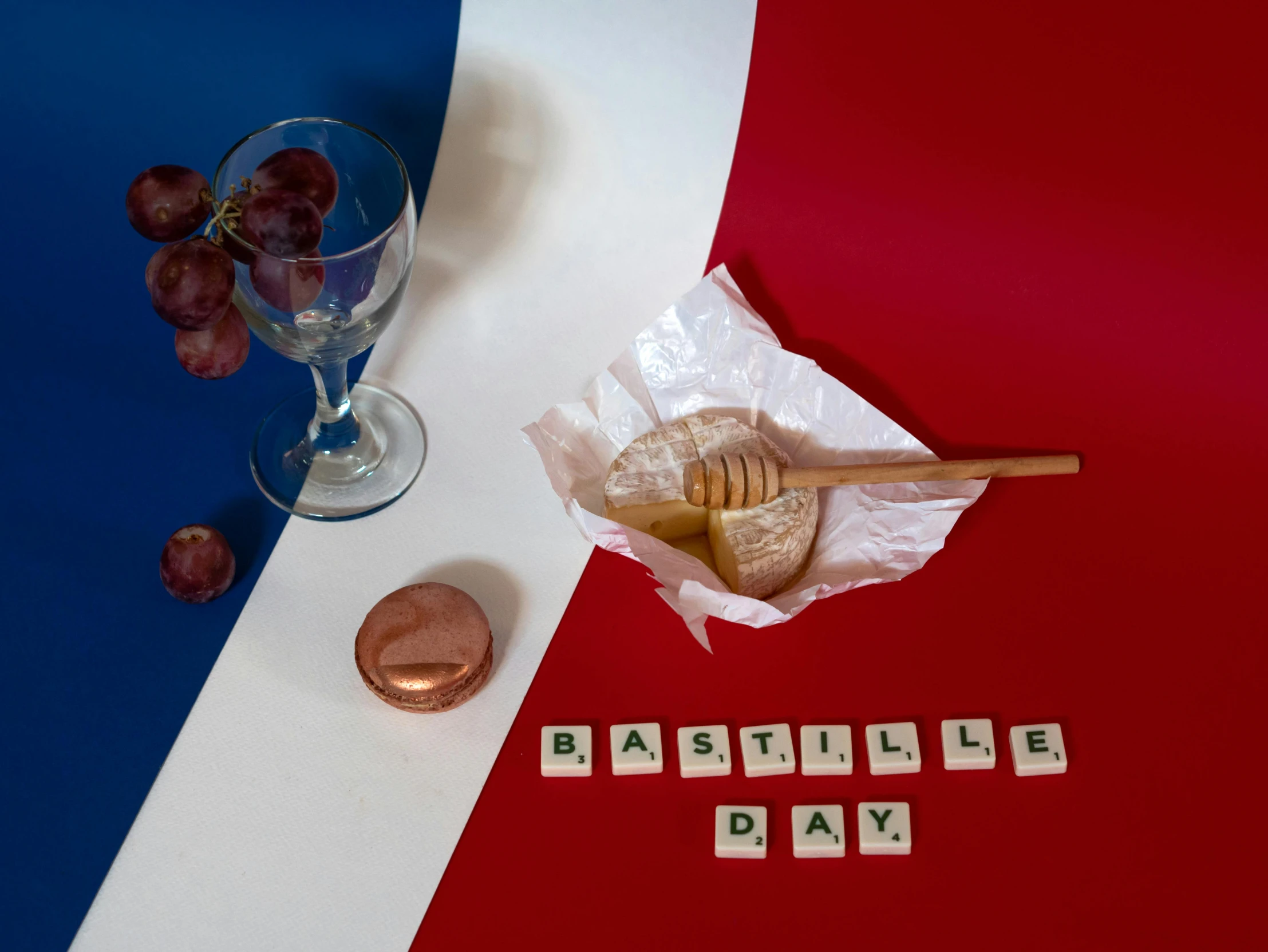 a glass of wine sitting on top of a red, white and blue table, an album cover, inspired by Édouard Detaille, unsplash, de stijl, deconstructed waffle, good day, made of bronze, french flag