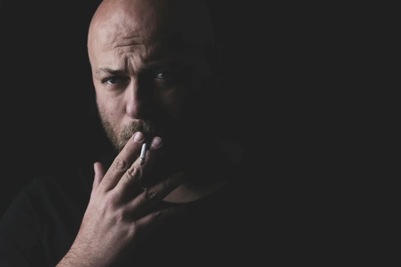 a man smoking a cigarette in the dark, pexels contest winner, hyperrealism, bald with short beard, mike judge, album cover, unhappy