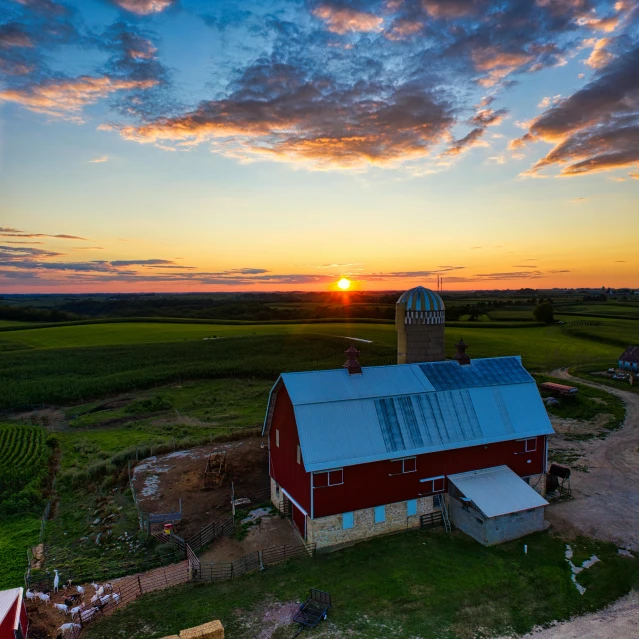 a red barn sitting on top of a lush green field, a picture, by Arnie Swekel, pexels contest winner, sun set, view from above, wisconsin, 2 5 6 x 2 5 6 pixels