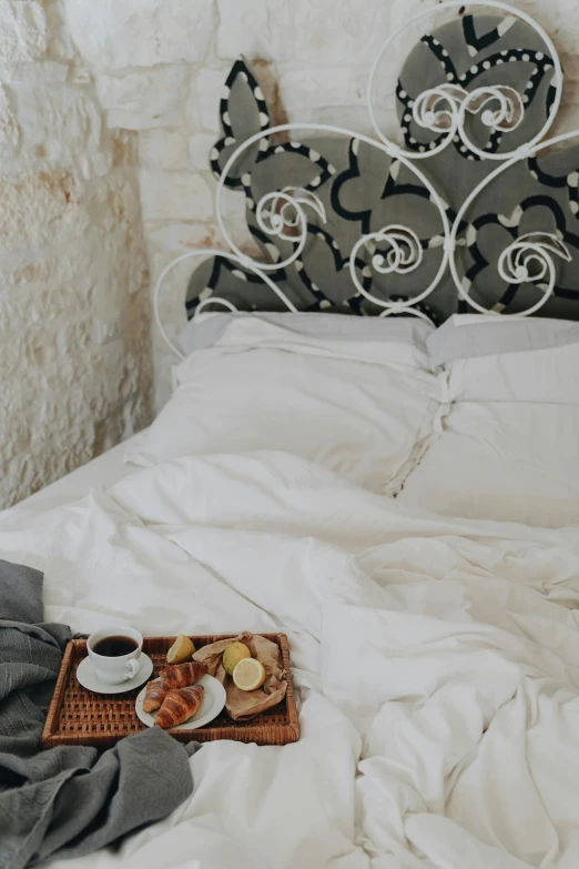 a tray of food sitting on top of a bed, inspired by Riad Beyrouti, trending on unsplash, baroque, white bed, sleepwear, wall, manuka