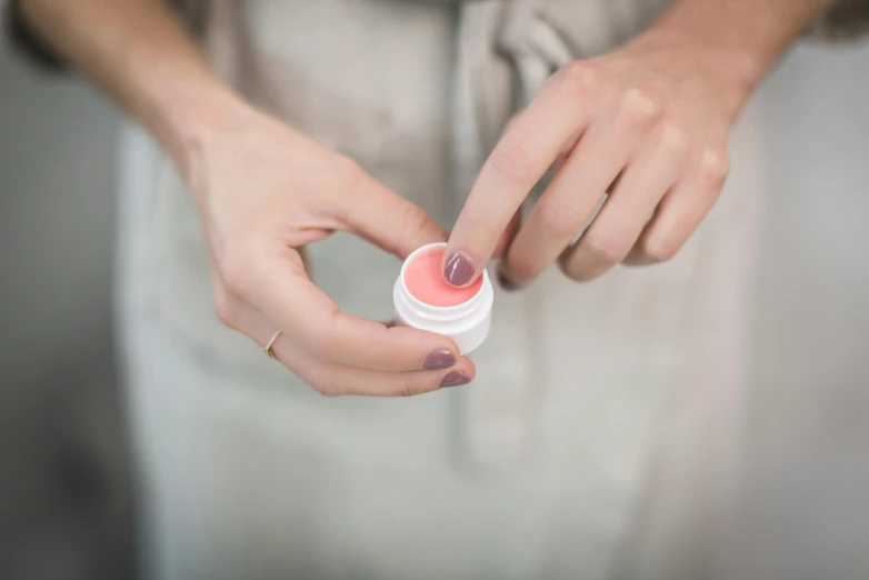 a close up of a person putting something in a jar, by Emma Andijewska, putting on lipgloss, wearing pink floral chiton, silicone skin, lavender blush