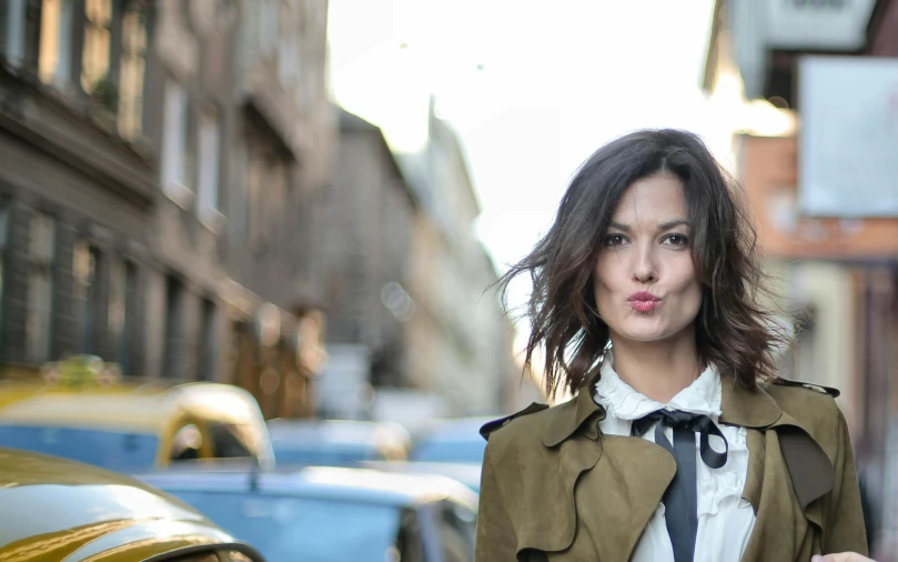 a woman in a trench coat and tie walking down a street, by Giuseppe Avanzi, pexels contest winner, renaissance, cute face, messy shoulder-length dark hair, lipstick, youtube thumbnail