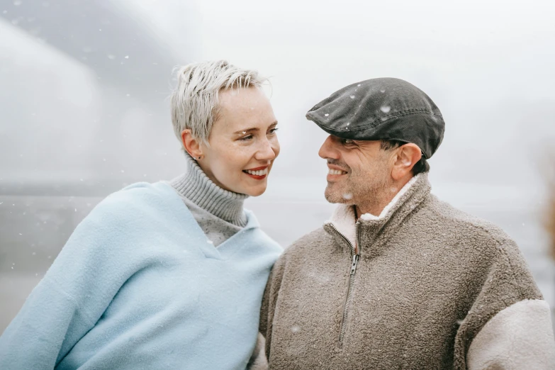 a man and woman standing next to each other in the snow, pexels contest winner, short grey hair, thumbnail, scandinavian, smiling couple