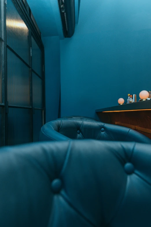 a living room with blue walls and leather furniture, unsplash, art nouveau, cocktail bar, blue, spa, half blue