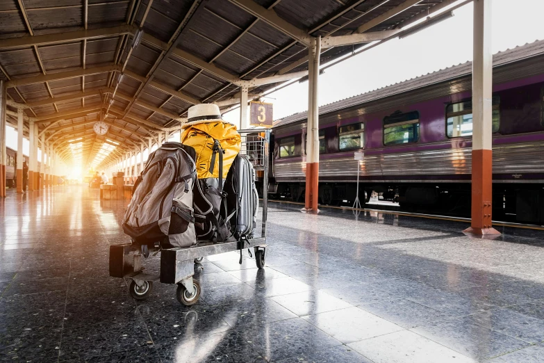 a luggage cart in a train station with a train in the background, by Tom Wänerstrand, shutterstock, bangkok, square, a backpack, morning sunrise