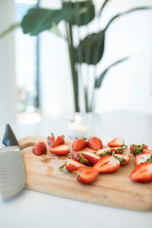 a wooden cutting board topped with sliced strawberries, by Andries Stock, pexels contest winner, morning coffee, sleek design, made of glazed, indoor smooth light