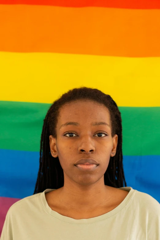 a woman standing in front of a rainbow flag, by Lily Delissa Joseph, frontal portrait of a young, close - up photo, emmanuel shiru, portrait n - 9