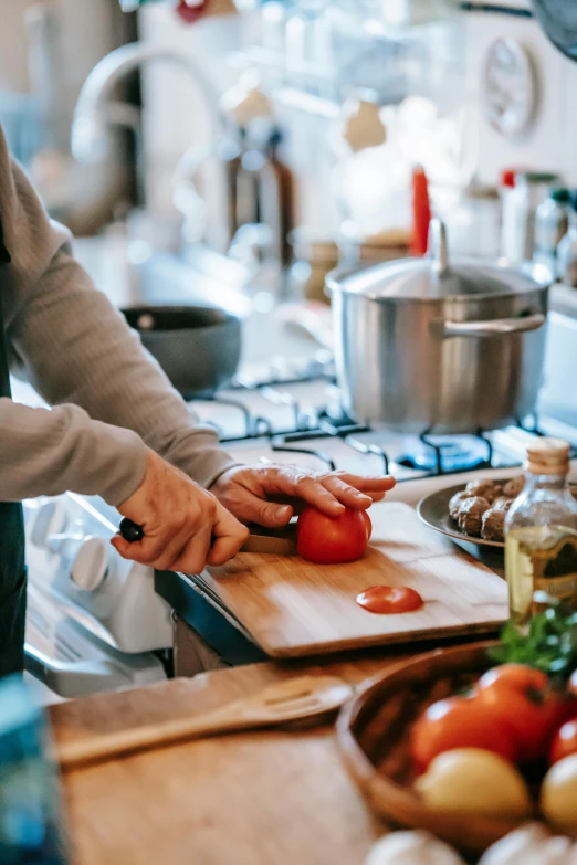 a woman cutting tomatoes on a cutting board in a kitchen, pexels contest winner, steaming food on the stove, a handsome, gif, hands on counter