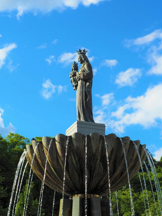 a water fountain with a statue on top of it, majestic saint woman, from the distance, with a crown, centred in image