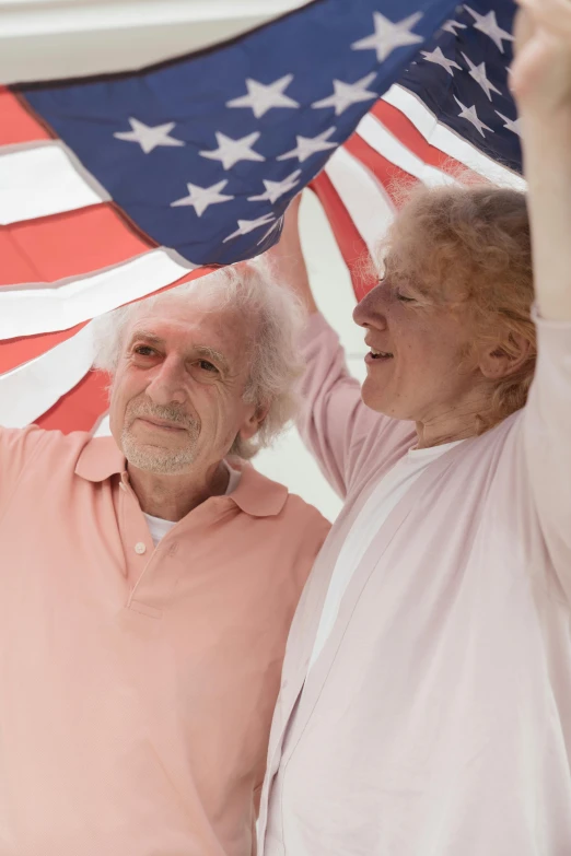 a man and a woman holding an american flag, white hair floating in air, elderly, trending on imagestation, ( ( theatrical ) )