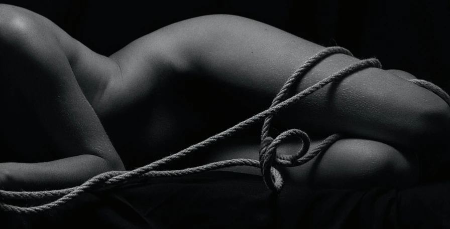 a black and white photo of a woman tied up, inspired by Robert Mapplethorpe, pexels contest winner, figurative art, rope bondage, album cover, curving, photo of a black woman