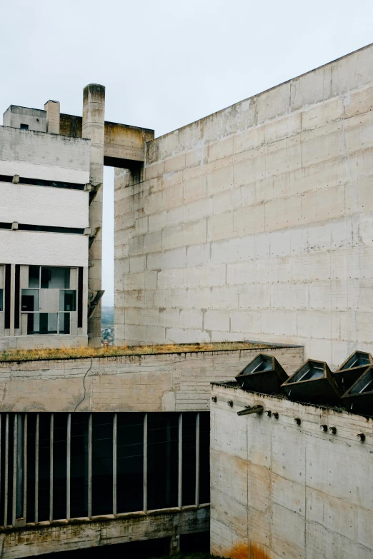 a man riding a skateboard on top of a cement building, inspired by Peter Zumthor, unsplash, brutalism, soviet yard, overview, white concrete, 1990s photograph