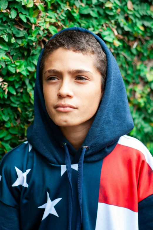 a close up of a person wearing a hoodie, inspired by Carlos Berlanga, stars and stripes, teen boy, official store photo, brook