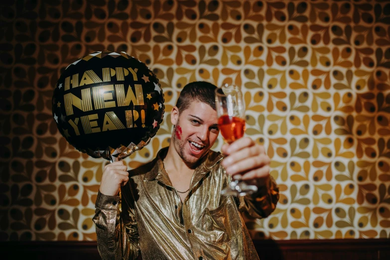 a man holding a balloon and a glass of wine, new years eve, liam brazier, holding a gold bag, rex orange county