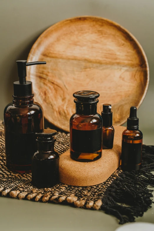 a wooden plate sitting on top of a table next to bottles of essential oils, unsplash, renaissance, black and brown colors, thumbnail, skin care, victorian alchemists