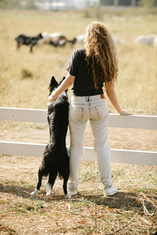 a woman standing next to a black and white dog, unsplash, pony facing away, farms, denim, college