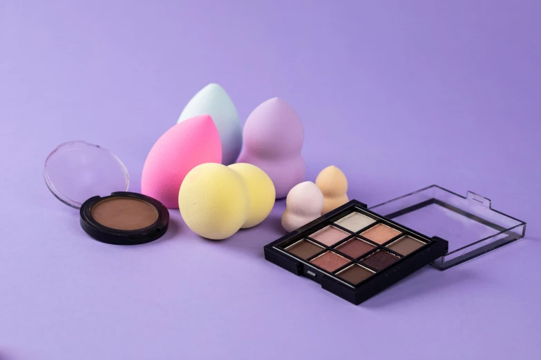 makeup brushes and sponges on a purple background, a still life, by Julia Pishtar, grid of eye shapes, translucent eggs, candy pastel, miniature product photo