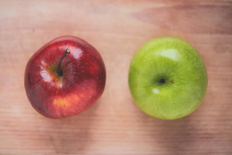 two apples sitting next to each other on a table, pexels, red and green, a wooden, shot from 5 0 feet distance, face to face