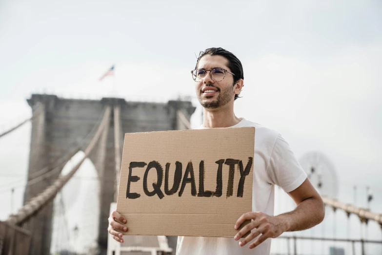 a man holding a sign that says equality, a colorized photo, trending on pexels, renaissance, background image, man with glasses, instagram post, no watermarks