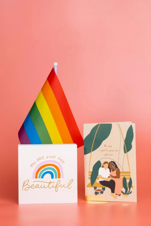 two cards and a rainbow flag on a pink background, on a pedestal, beautiful visuals, displayed