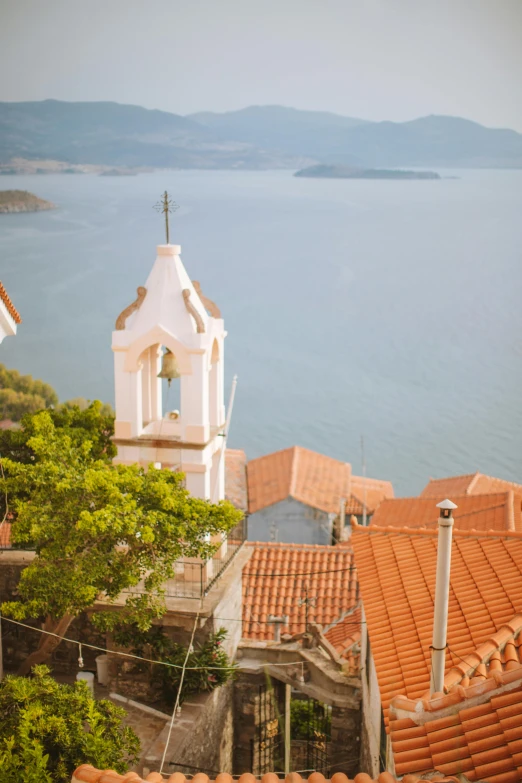 a clock tower on top of a building next to a body of water, croatian coastline, looking down on the view, orange roof, slide show