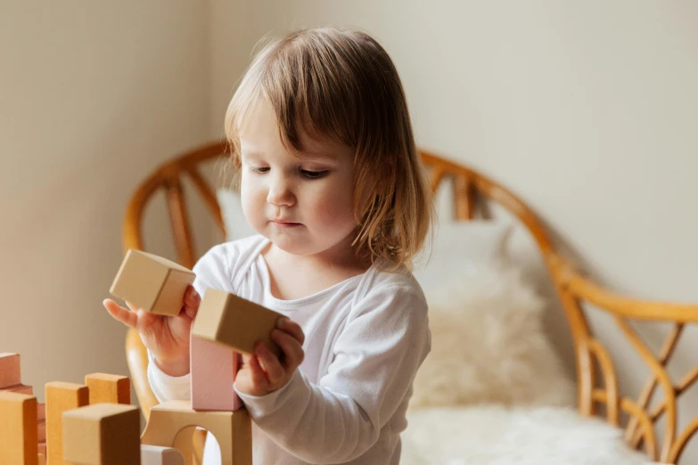 a little girl is playing with wooden blocks, inspired by Sarah Lucas, pexels contest winner, arts and crafts movement, rosey cheeks, portrait of small, a wooden, 1 2 9 7