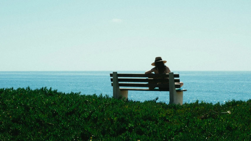 a man sitting on a bench overlooking the ocean, pexels contest winner, woman with hat, sydney park, lo-fi, oceanside