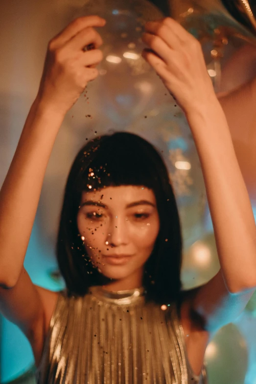 a woman holding a balloon over her head, trending on pexels, magical realism, glittery short black hair, infinity mirror, scattered golden flakes, kiko mizuhara