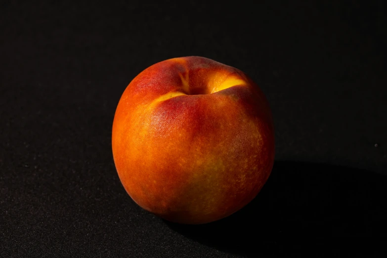 a peach sitting on top of a black surface, front facing the camera, eye - level medium - angle shot, detailed product shot, vanilla