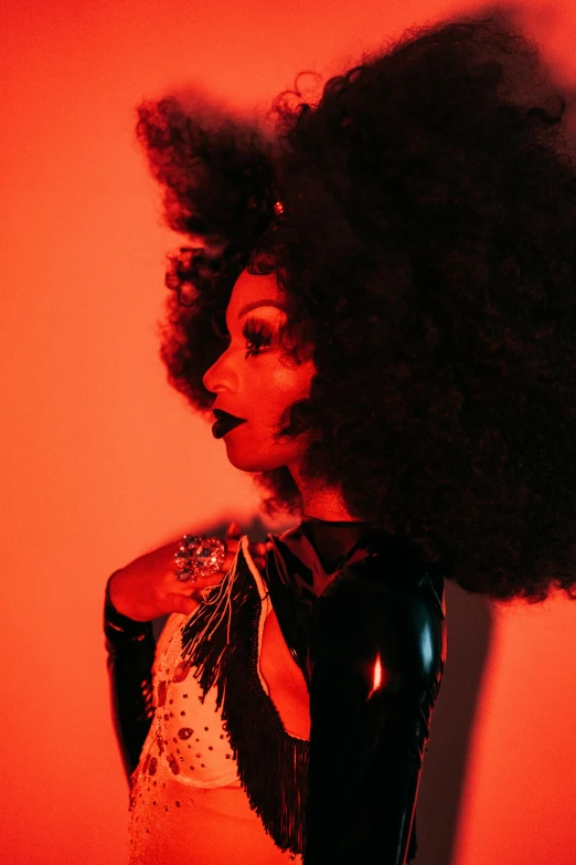 a woman with an afro standing in front of a red light, afrofuturism, burlesque psychobilly, deep black roots, photo of a woman, sza