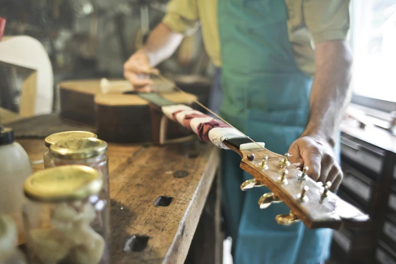 a man that is standing in a kitchen with a guitar, pexels contest winner, arts and crafts movement, in a workshop, resin, thumbnail, no cropping