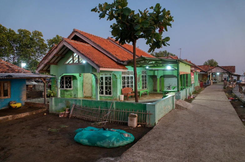 a green house sitting on the side of a road, by Basuki Abdullah, evening lighting, verdigris, residential area, afar