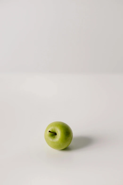 a green apple sitting on top of a white table, detailed product image, f / 1 1. 0, small nose, jaime jasso