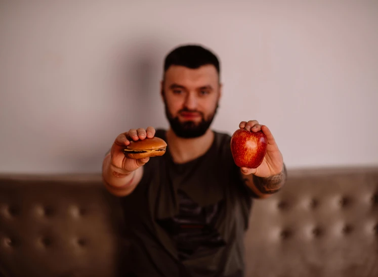 a man holding an apple and a hamburger, by Julia Pishtar, pexels contest winner, hasbulla magomedov, hypermasculine, indoor picture, 15081959 21121991 01012000 4k